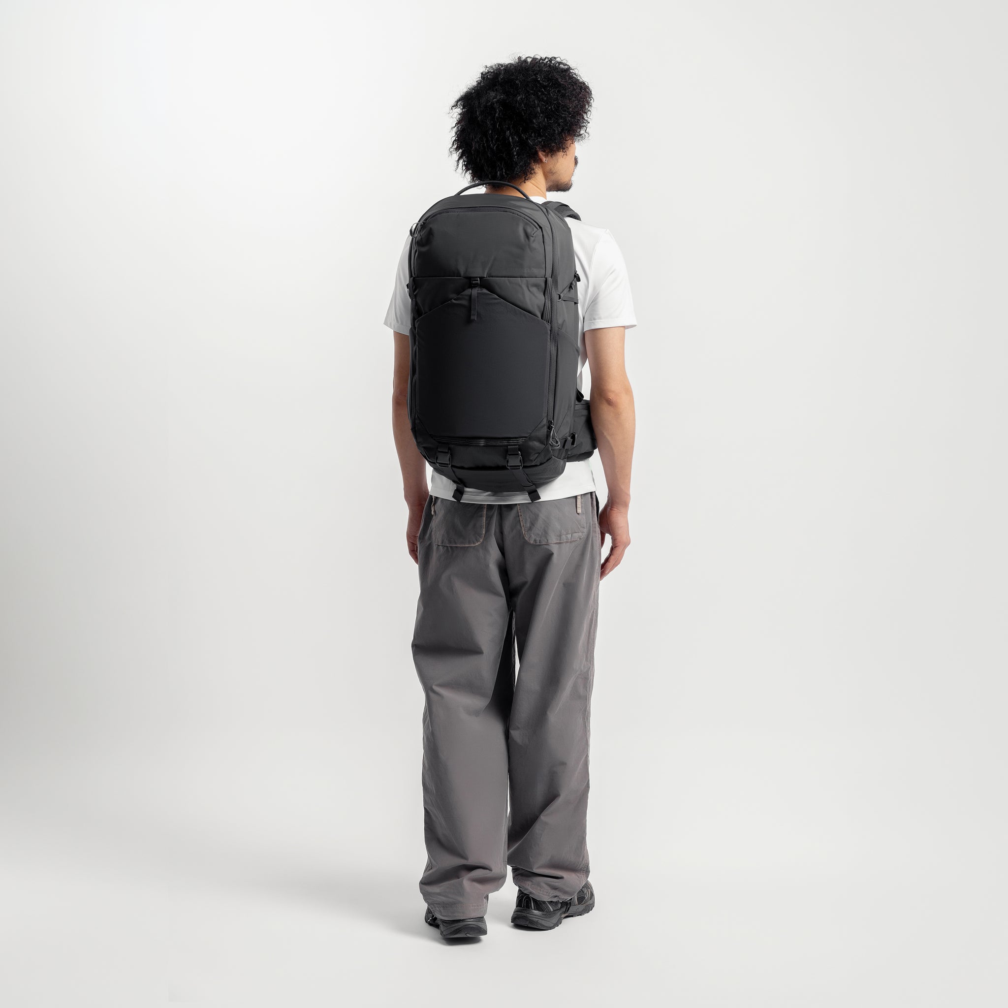 A man wearing the Motion Adventure Pack on his back facing away in Charcoal