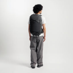 A man wearing the Motion Adventure Pack on his back facing away in Charcoal