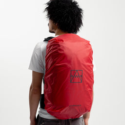 A studio shot of the Model wearing the Motion Adventure Pack 38L in Ash and Charcoal on his back with the attached rain cover over the top