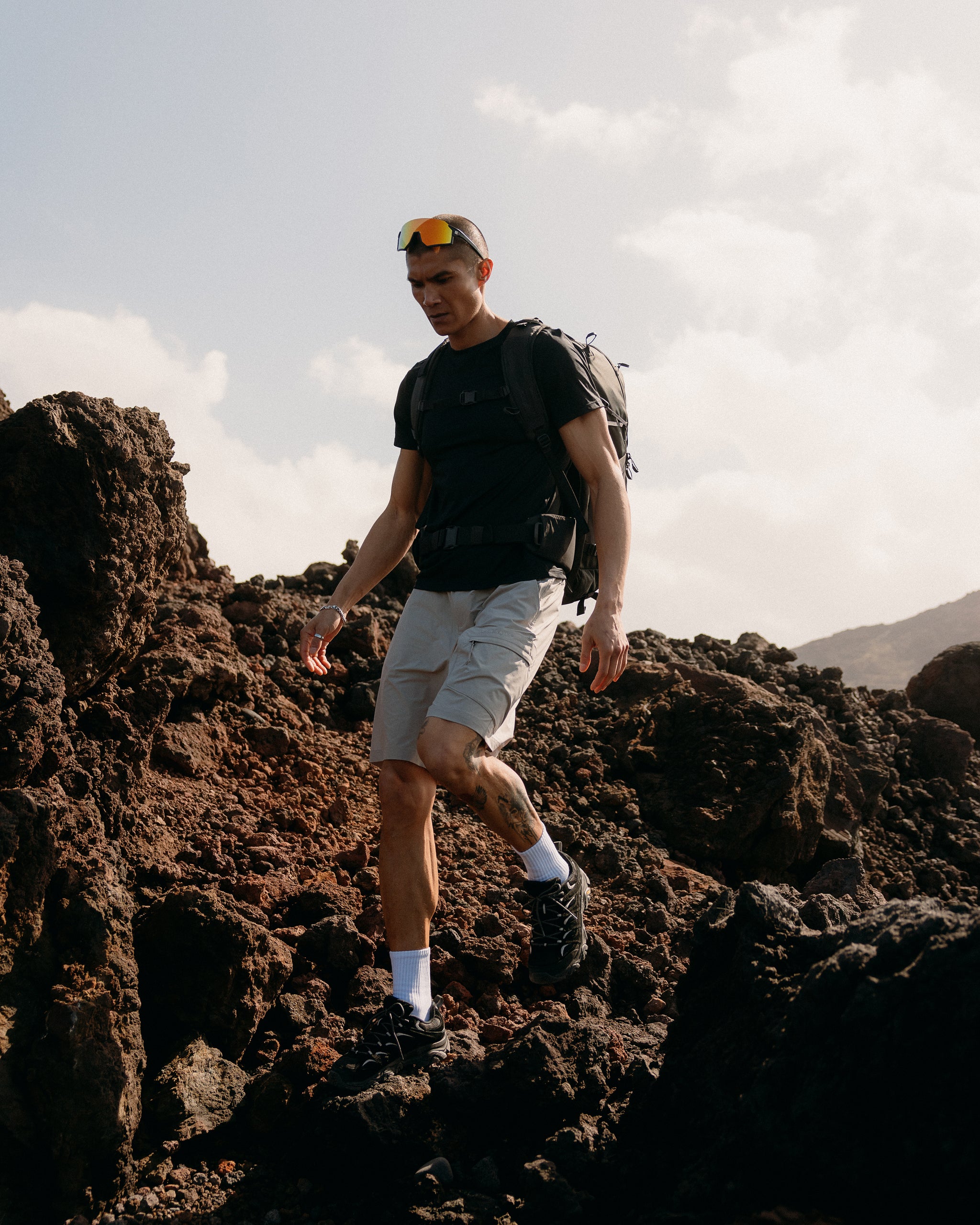 A man hiking over rocks wearing a Motion Adventure Pack 38L in Charcoal on his back