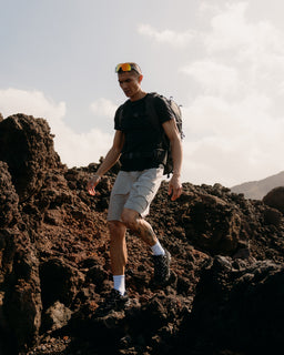 A man hiking over rocks wearing a Motion Adventure Pack 38L in Charcoal on his back