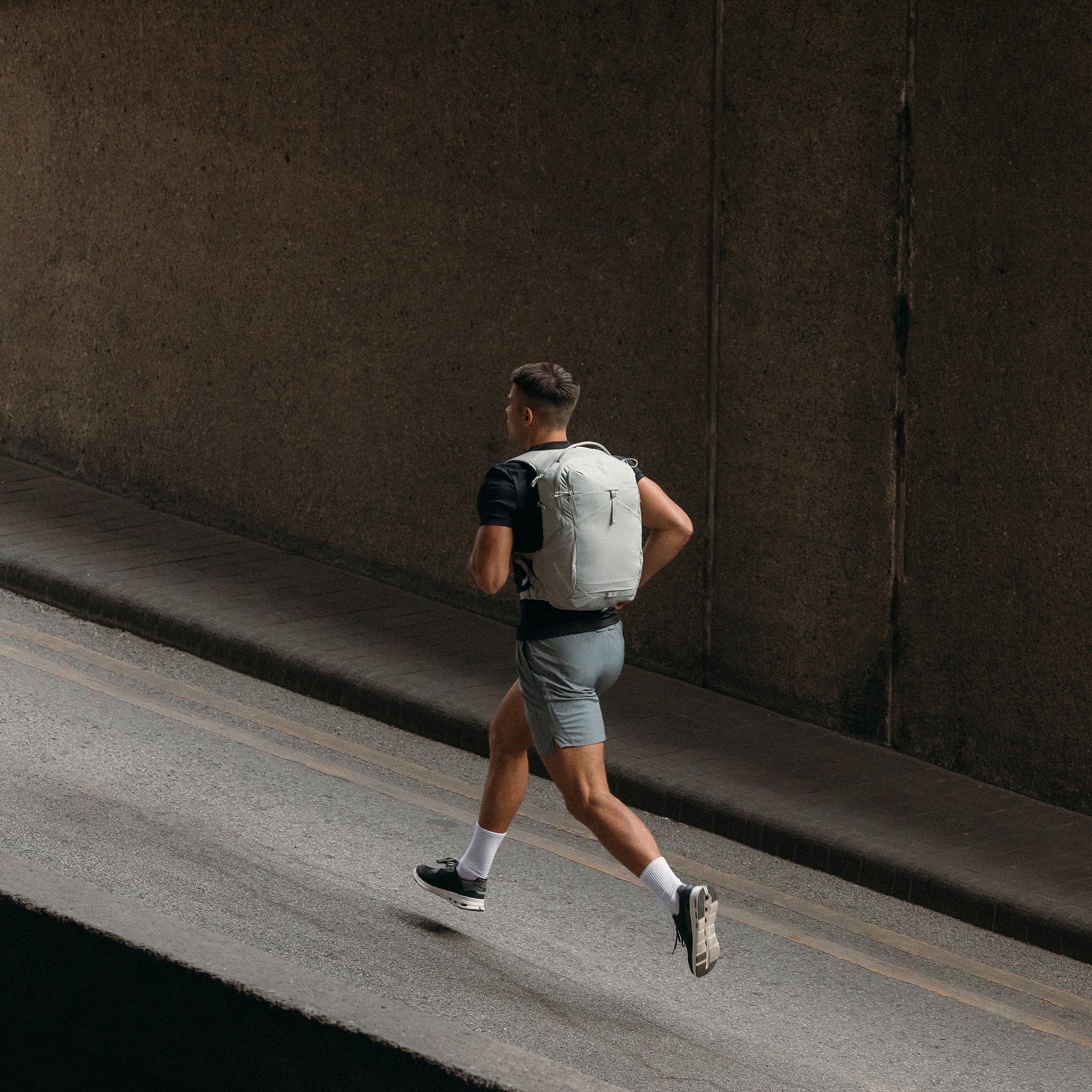 A man running up the road with an ash motion backpack 20l on his back