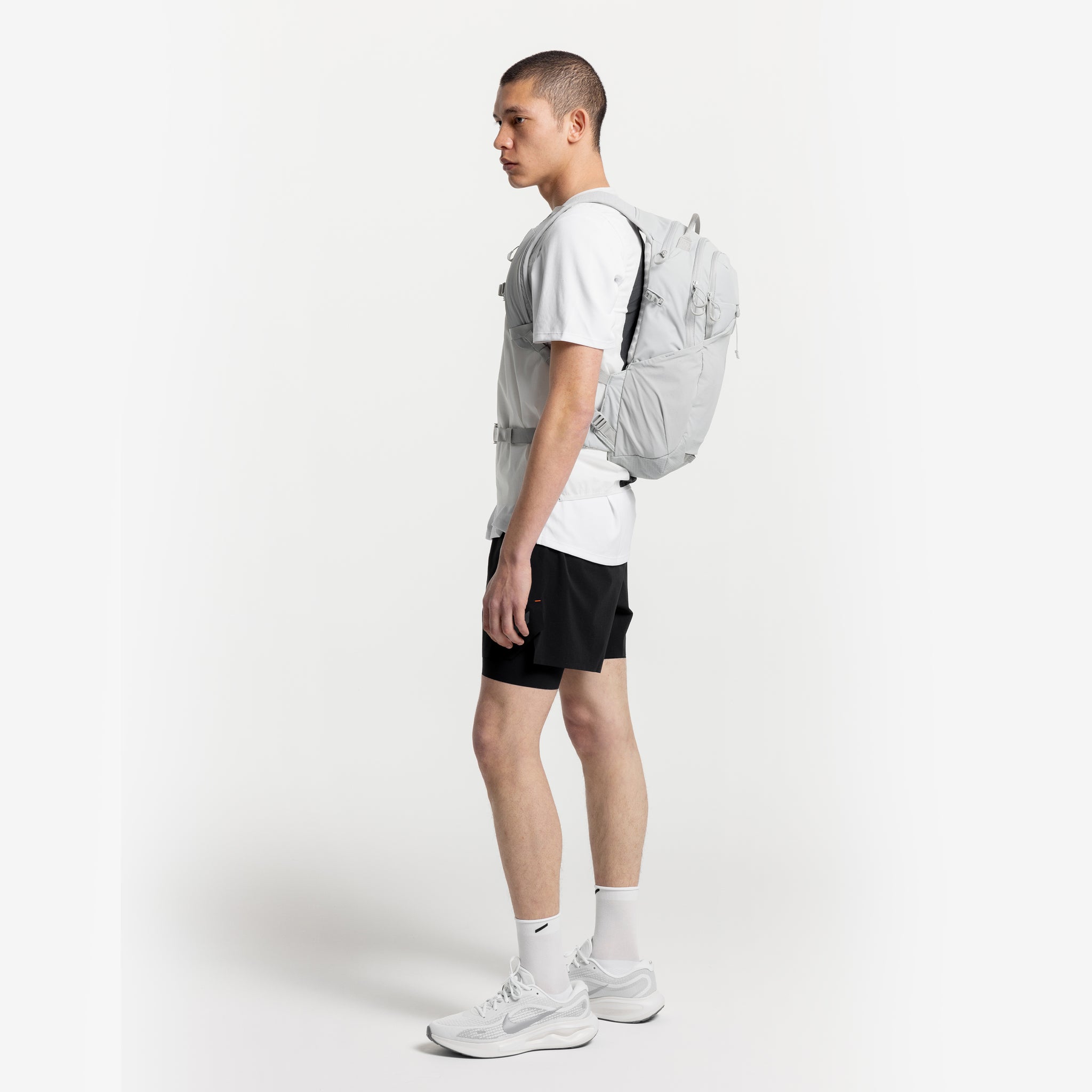 A studio shot of a man standing side on wearing an Ash Motion Backpack 20L