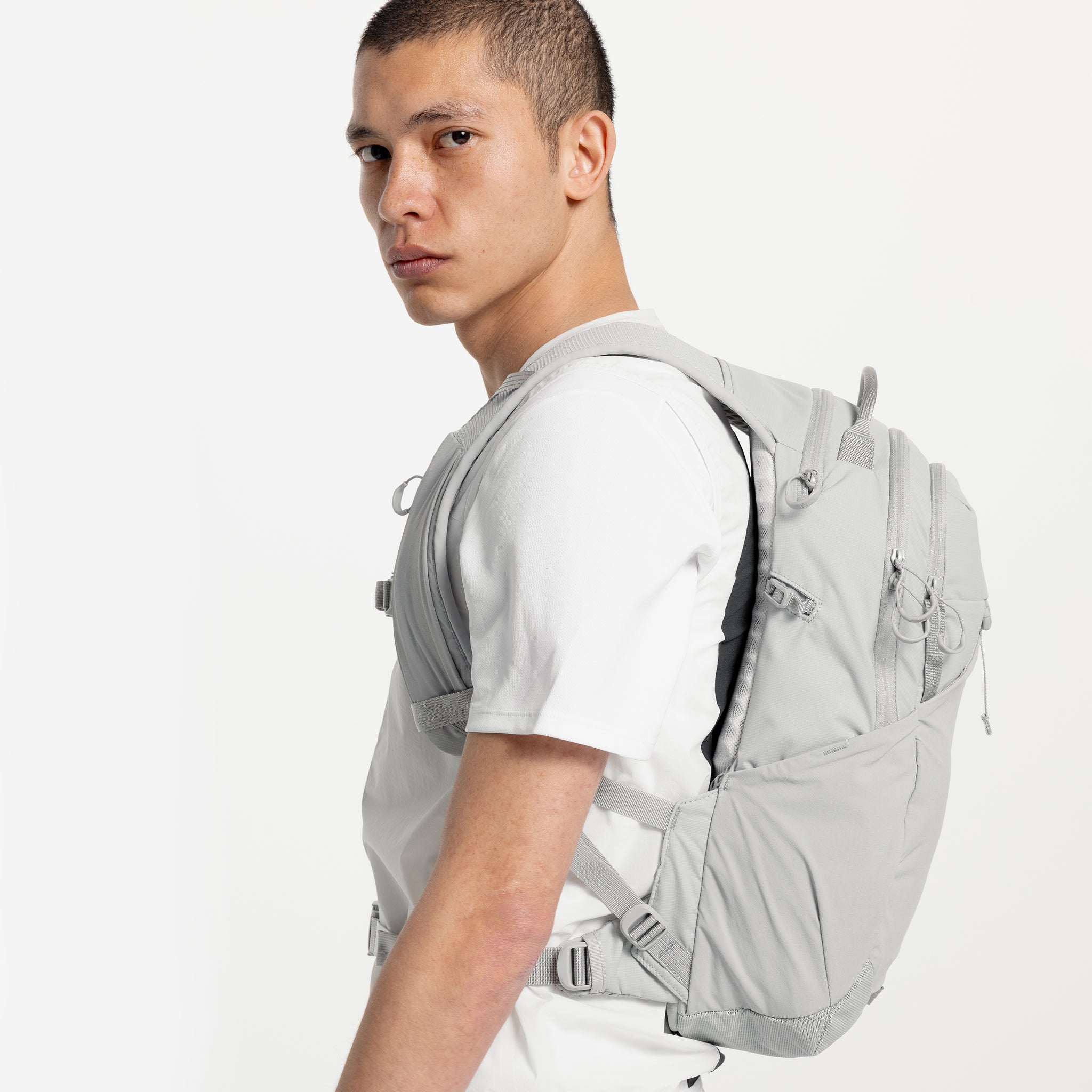 A model standing sided on looking into the camera wearing an Ash Motion Backpack 20L on his back