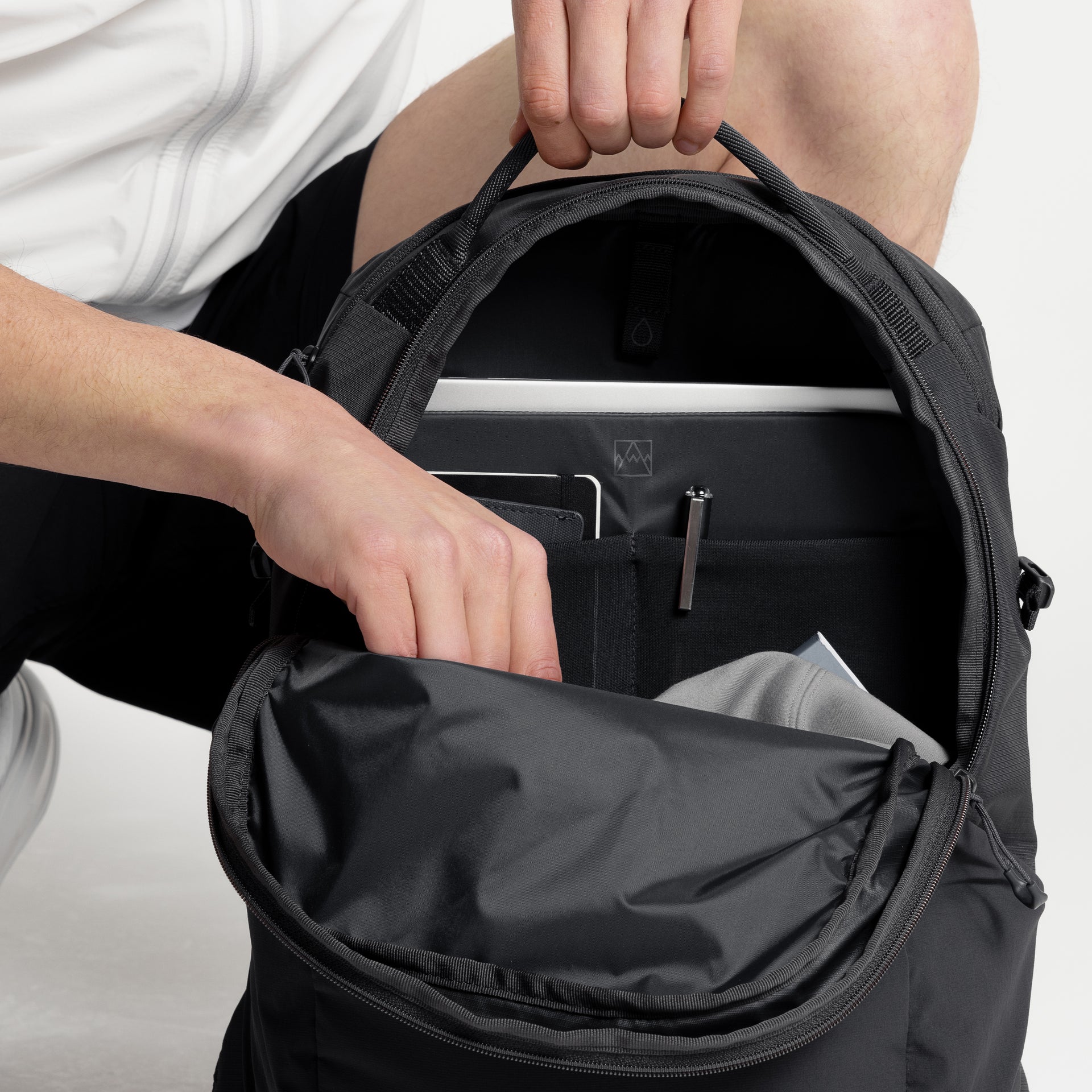 A studio shot of the interior organisation of the Charcoal Motion Backpack 20L  as well as Magma and Ash Backpack 20Ls