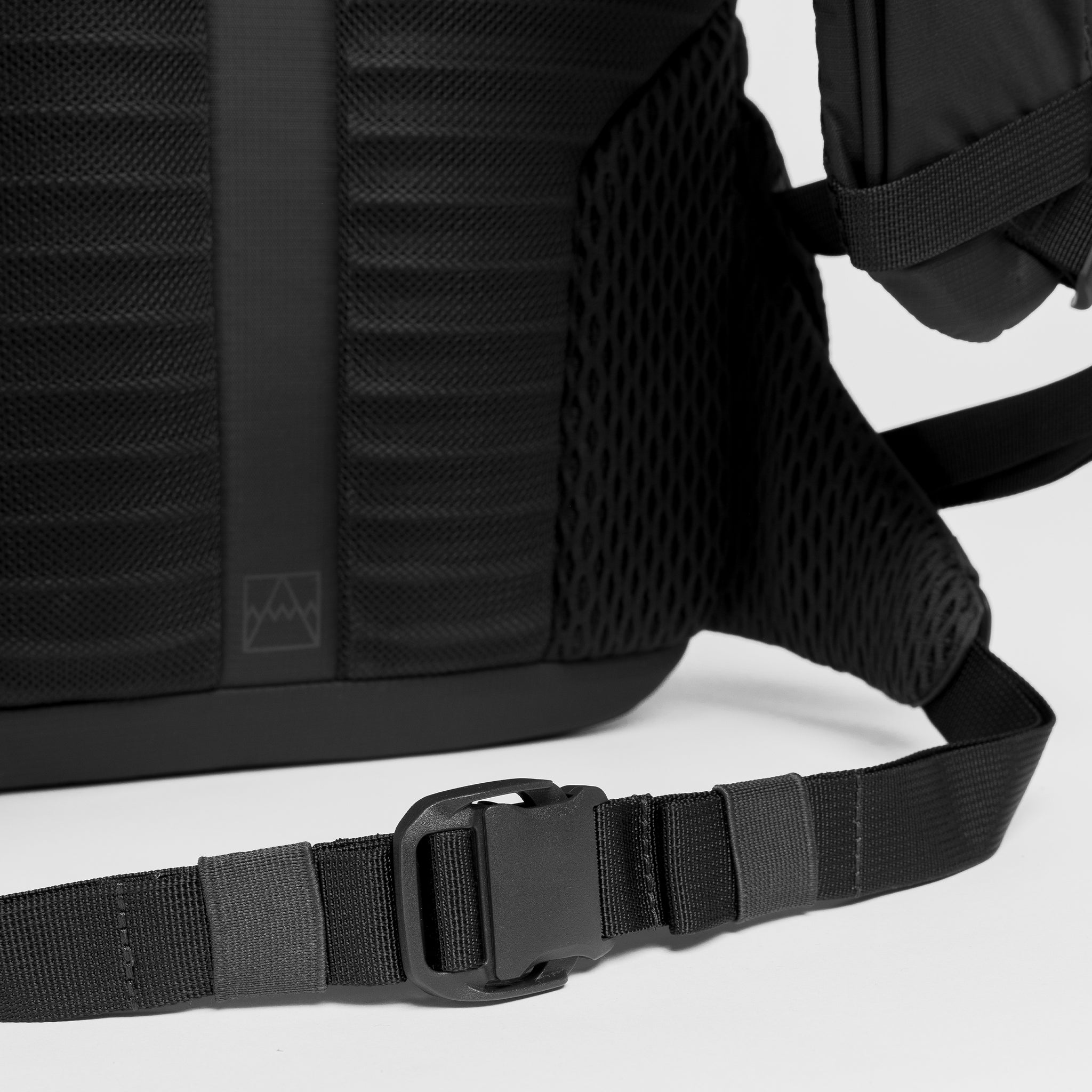 A studio shot of the a close up of the waist strap and easy-release clip on the Charcoal Motion Backpack 20L as well as Magma and Ash Backpack 20Ls