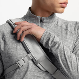 A studio shot of the shoulder strap and reflective logo on the Motion Sling 15L in Ash, Charcoal and Magma