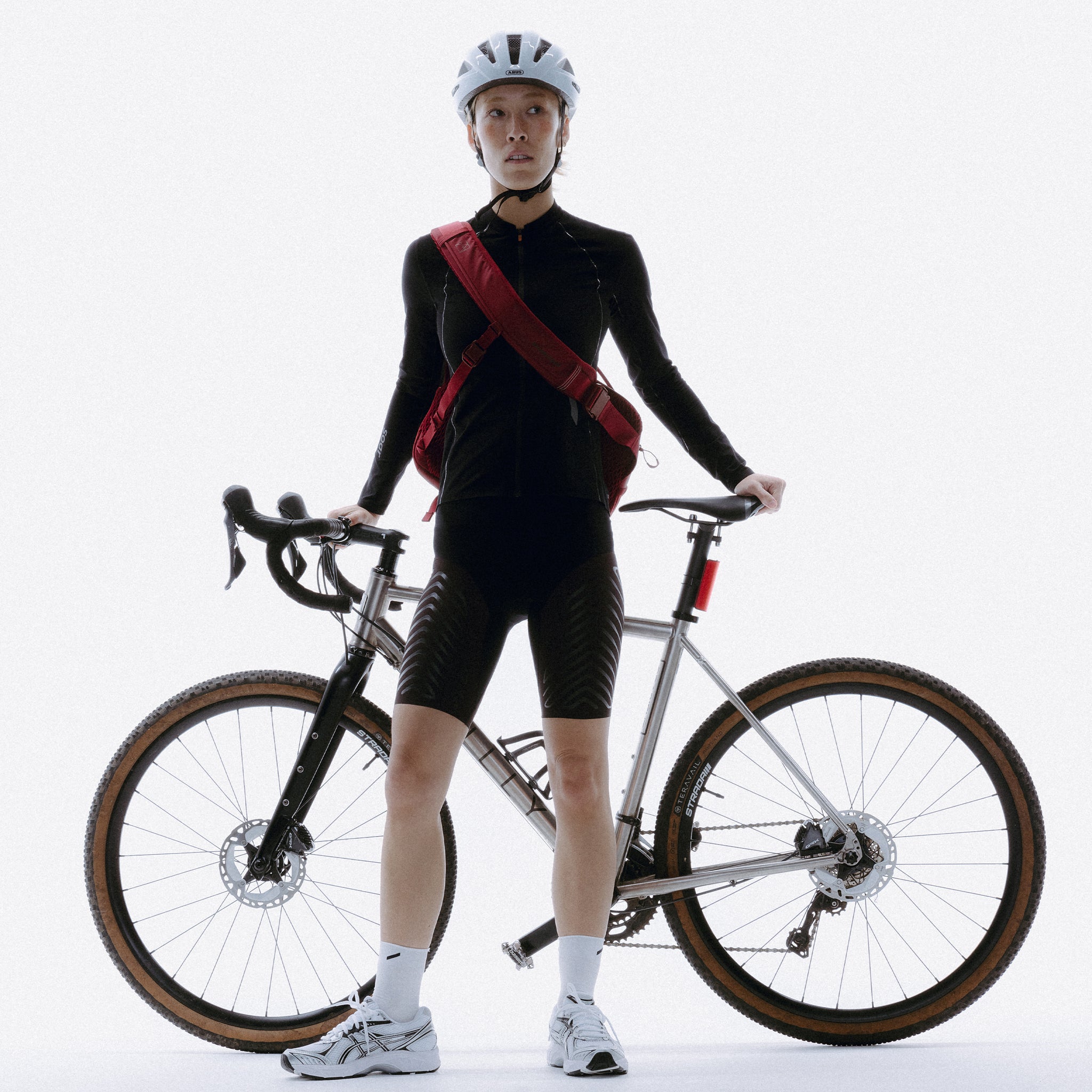 A woman standing next to her bike wearing a Magma motion sling 15l as a crosbsody