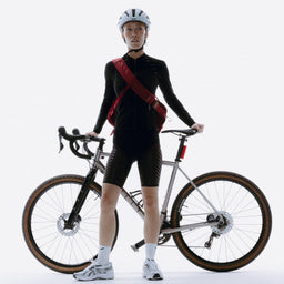 A woman standing next to her bike wearing a Magma motion sling 15l as a crosbsody