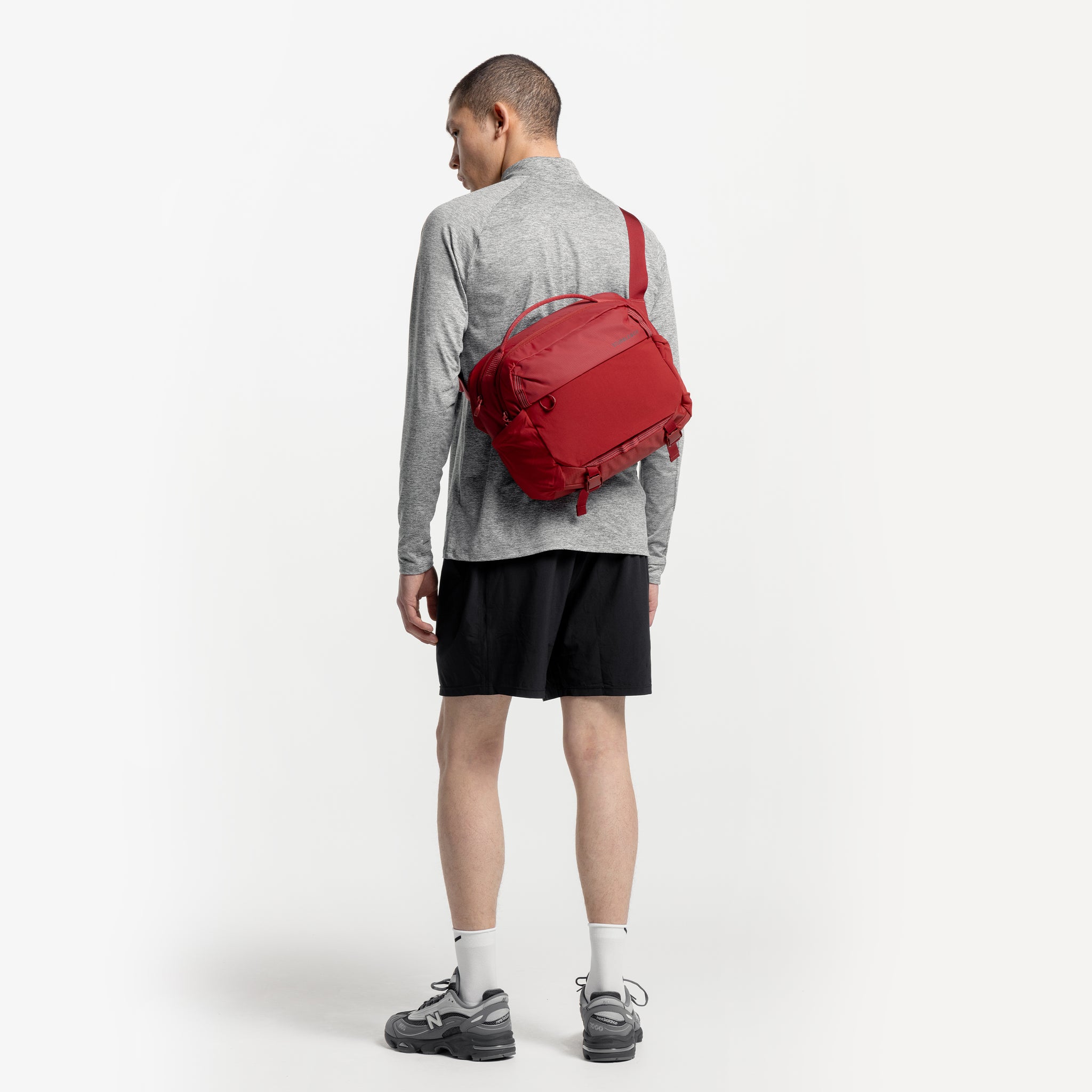 A studio shot of a model facing away wearing a Magma Motion Sling 15L on his back