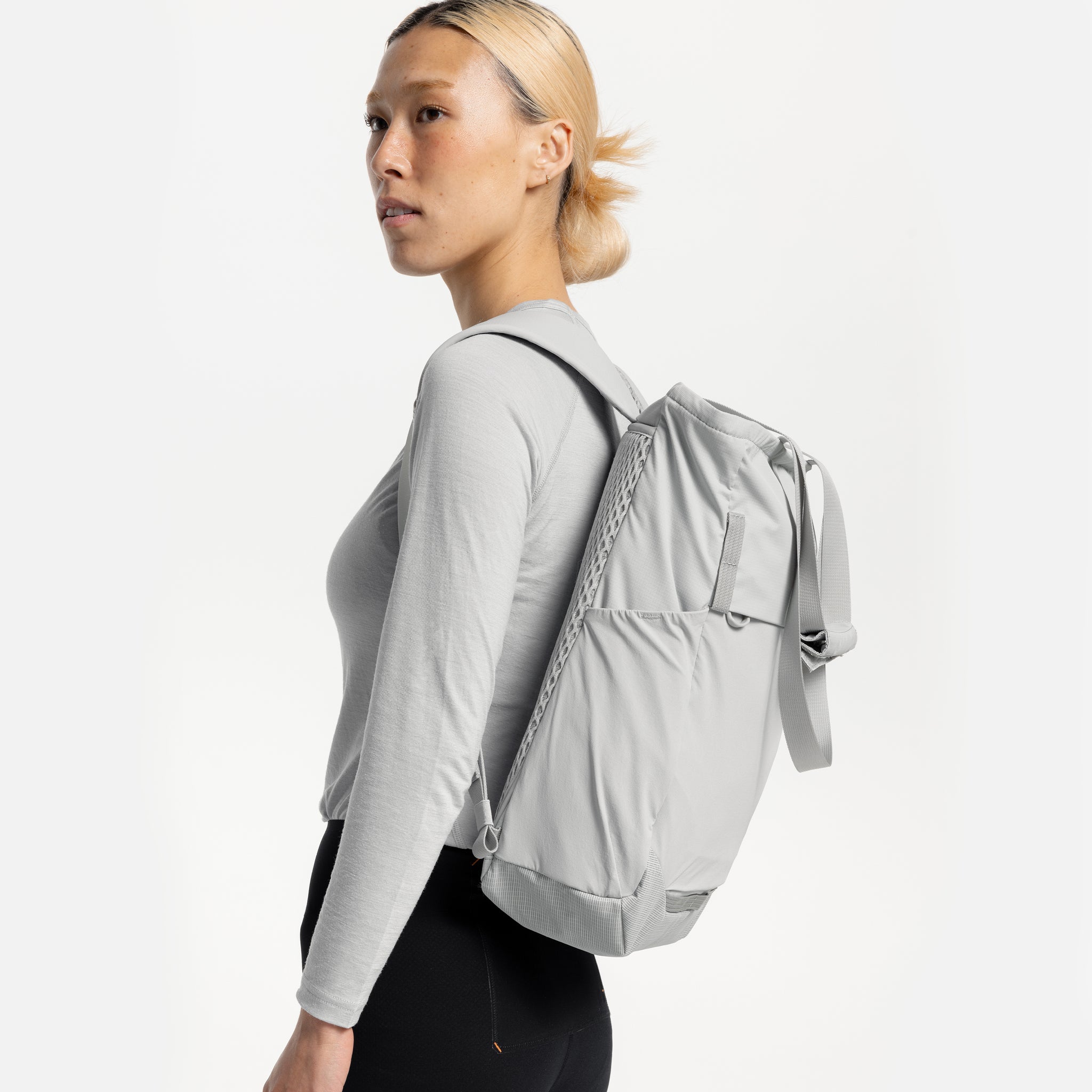 A woman standing side on with an Ash Motion Tote Pack 18L on her back