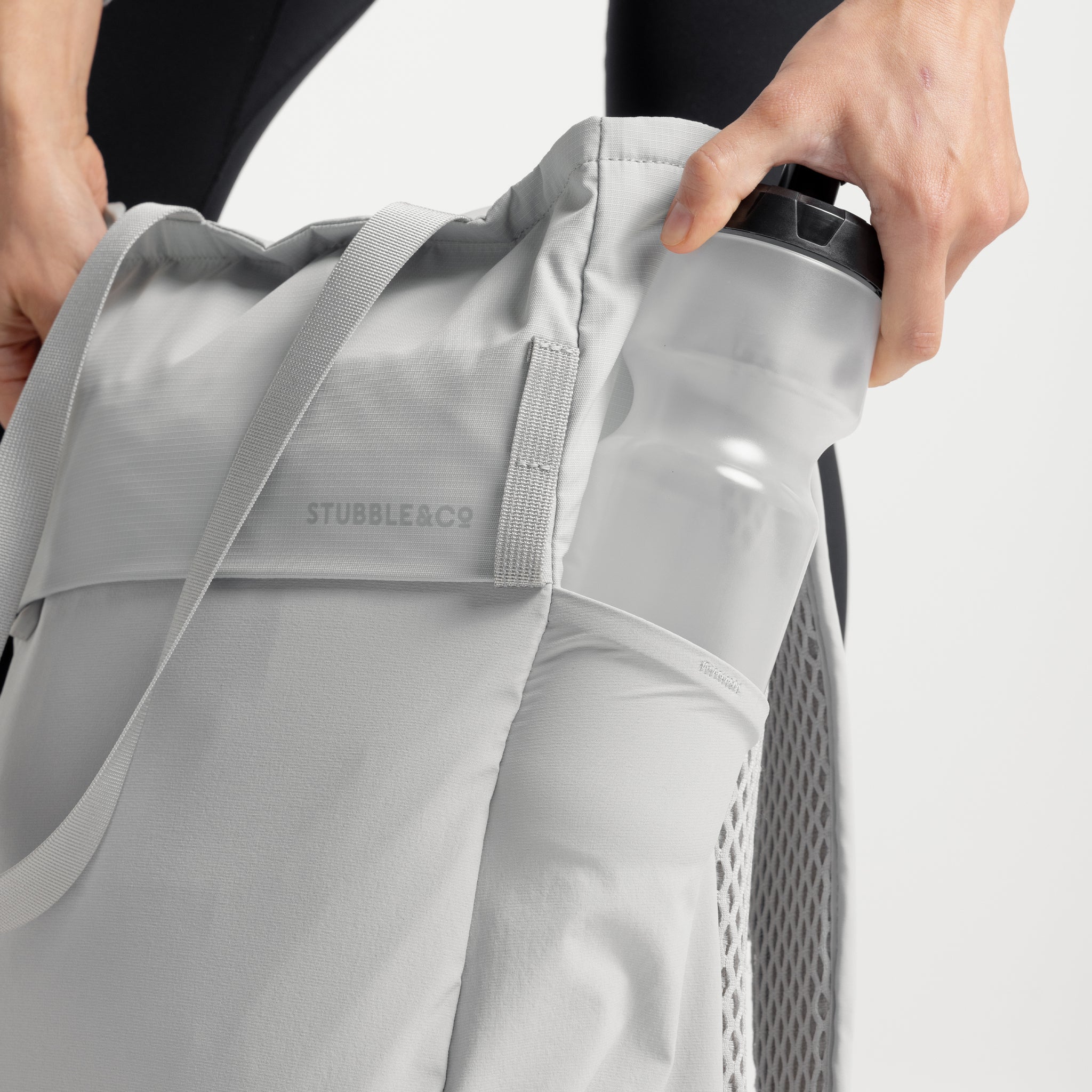 A studio shot of the side elasticated bottle pocket on the Motion Tote Pack 18L in Ash, Magma and Charcoal