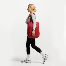A studio shot of a woman walking with a Magma Motion Tote Pack 18L on her shoulder