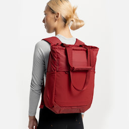 A model standing in a studio facing away from the camera wearing a Magma Motion Tote Pack 18L on her back