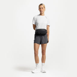 A studio shot of the Charcoal Motion Waist Pack 2L on her front around her waist