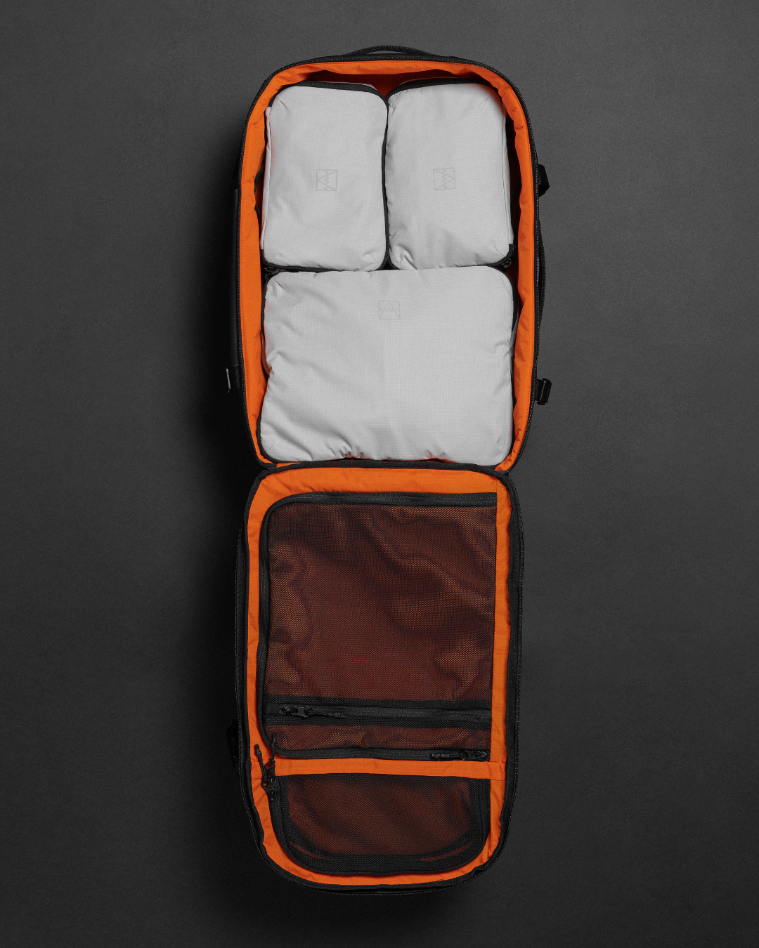 An open Hybrid Backpack with an orange interior, showing three Off-White Packing Cubes and a mesh compartment.