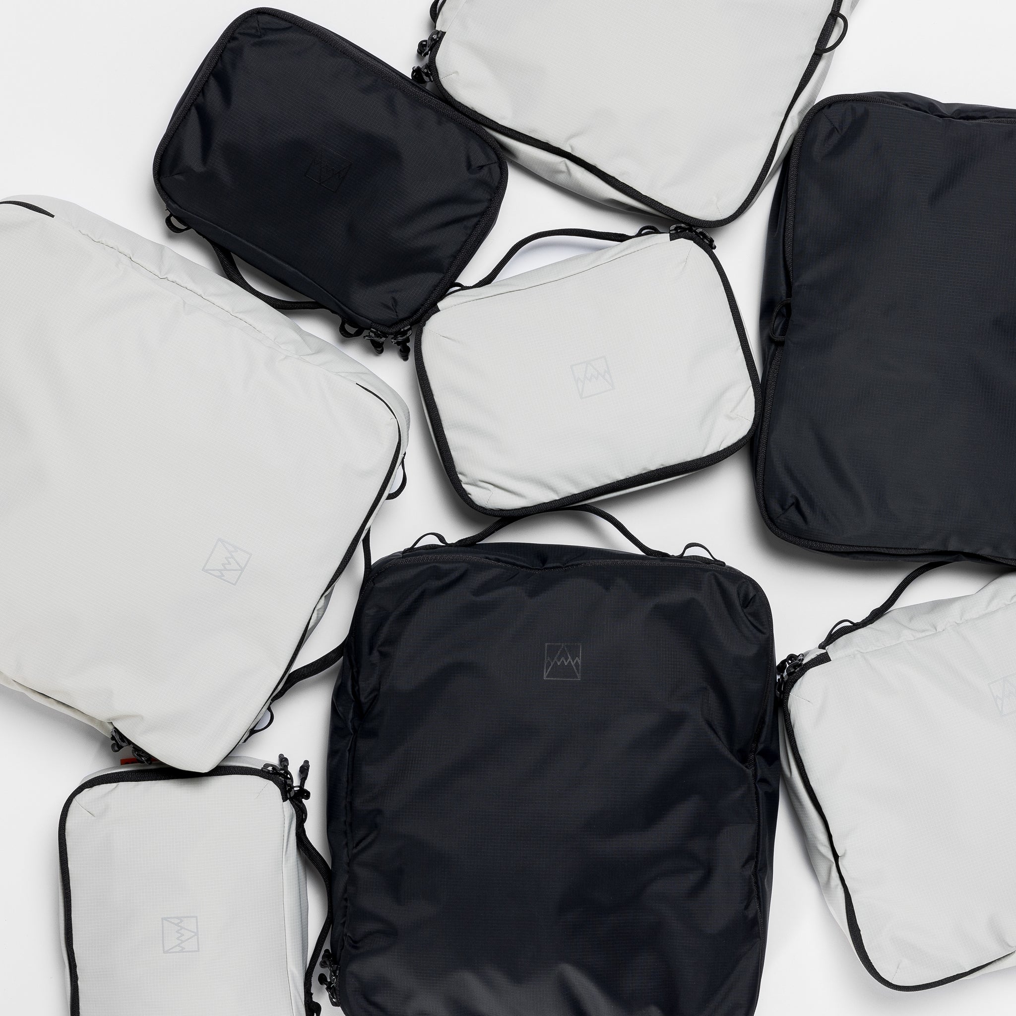 A studio shot of all the packing cube sizes in black and Off-White