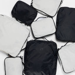 A studio shot of all the packing cube sizes in black and Off-White