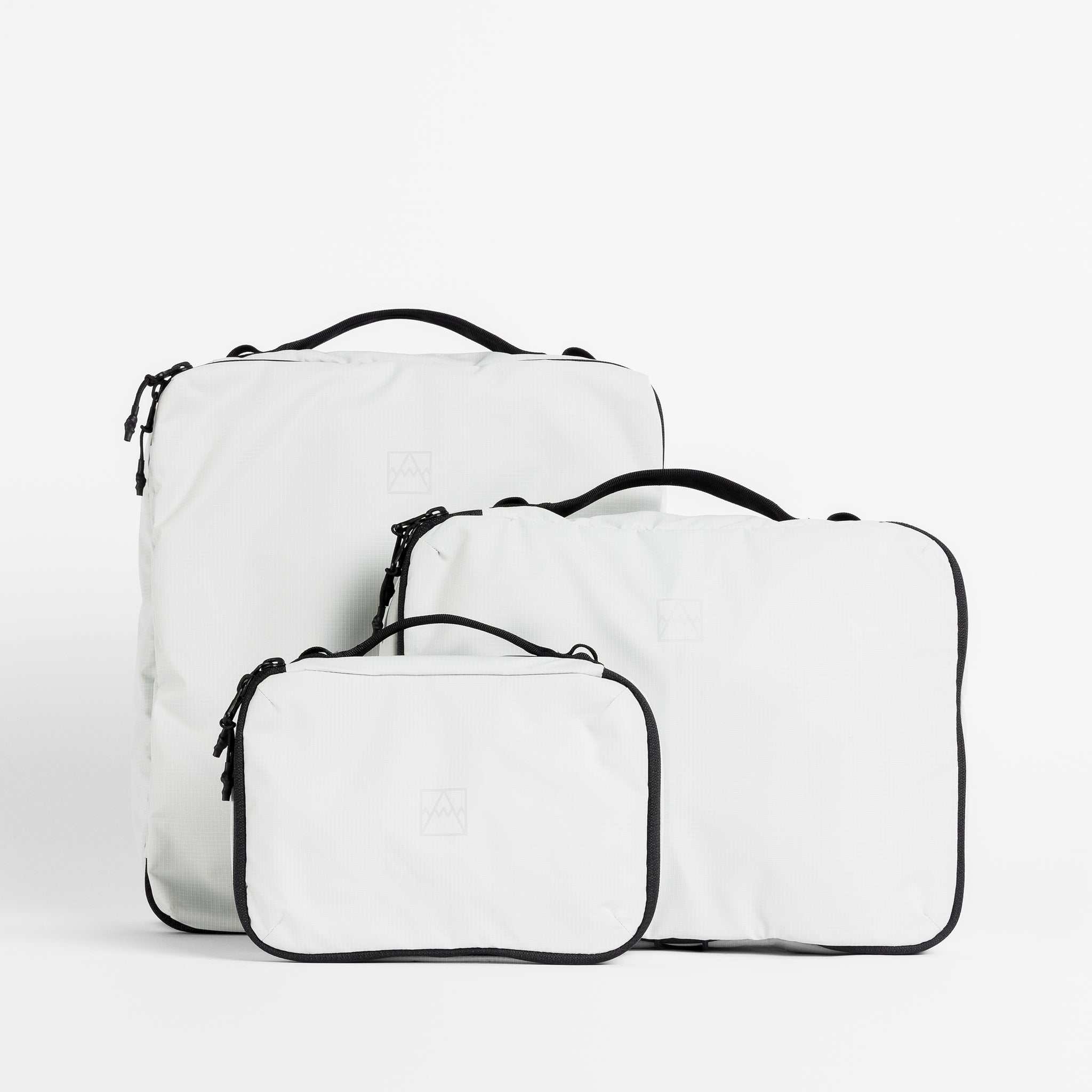 A studio shot of all the packing cube sizes in Off-White