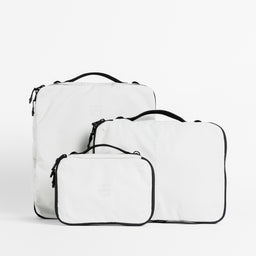 A studio shot of all the packing cube sizes in Off-White