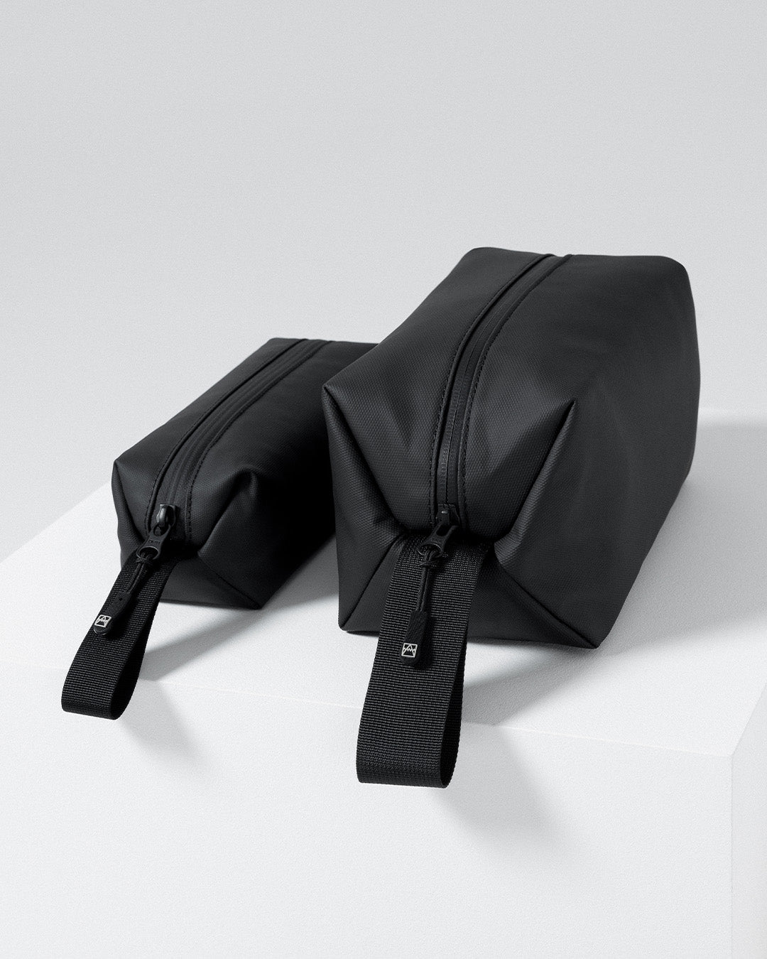 A studio shot of the Wash Bag and Wash Bag Mini side by side  Sand