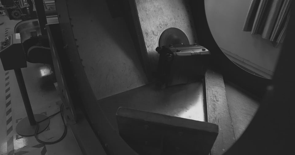 black hardshell suitcase being testing in a factory for durability.