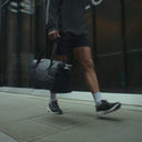 A campaign video for the gym duffel 25L in All Black showing a man going to the gym and a woman going on a run and doing yoga