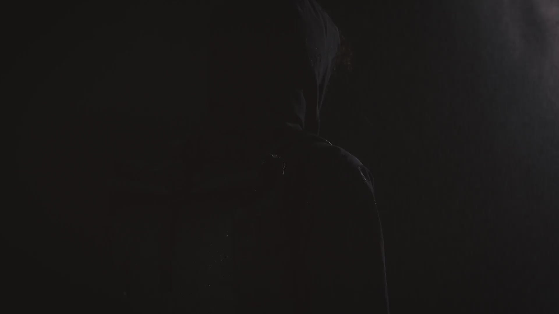 A video of a man standing with a roll top 20l in black on his back whilst lights flash and water sprays