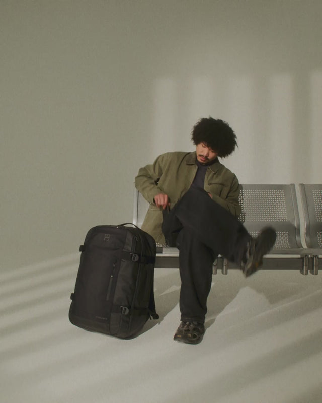 A video of a man sitting on an airport bench with a travel backpack 40l- 4:5