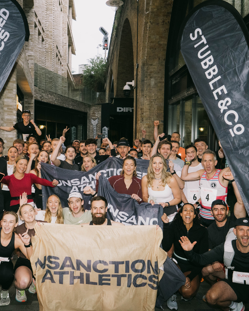 Group of people holding UNSANCTION ATHLETICS' banners in an urban setting and Stubble & Co flags