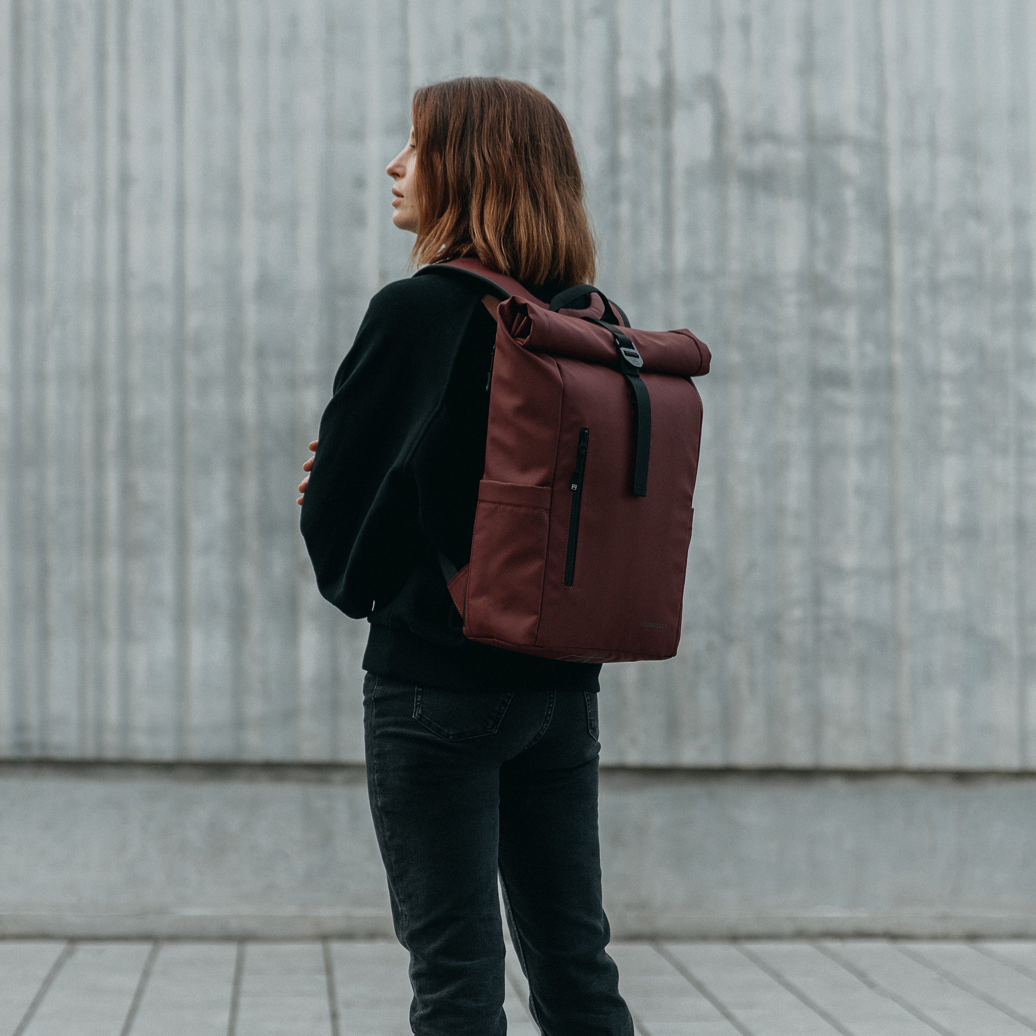 A woman wearing a Roll Top 15L on her back in Garnet Red
