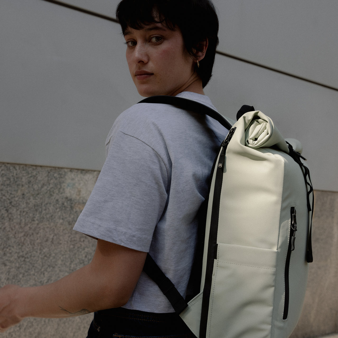 A woman standing side on showing the side of the Roll Top 15L in Soft Mint