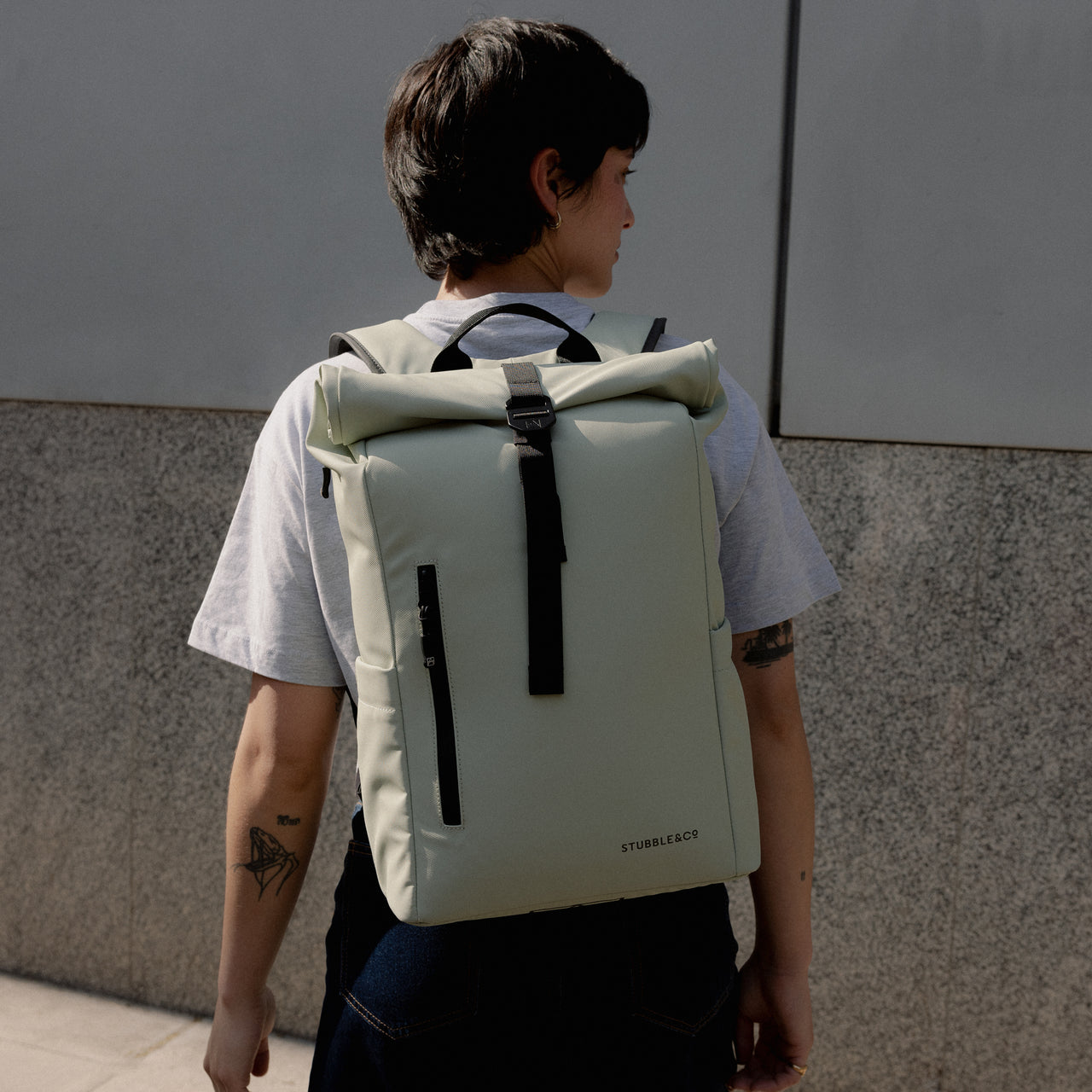 A woman walking away wearing a Roll Top 15L in Soft Mint on her back