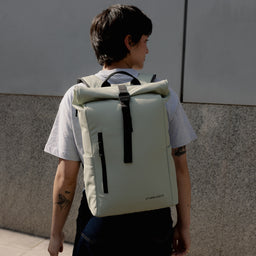 A woman walking away wearing a Roll Top 15L in Soft Mint on her back