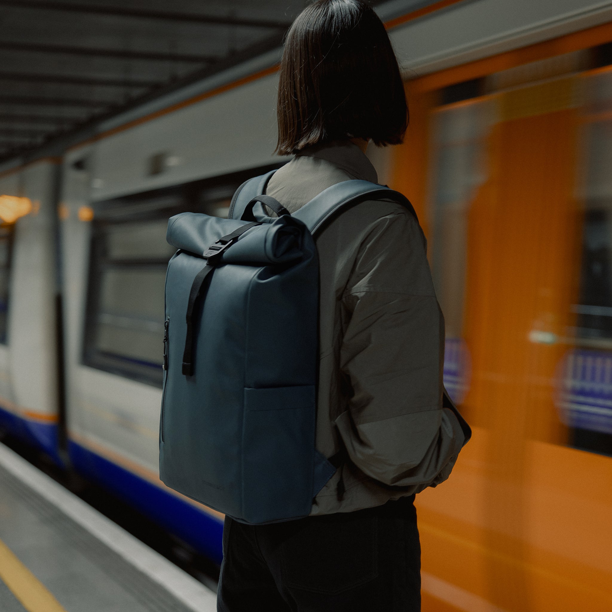 Women wearing the Roll Top 15L in Tasmin Blue at a train station