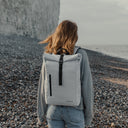 Women wearing The Roll Top 15L in Arctic White on a pebble beach with a cliff in the background