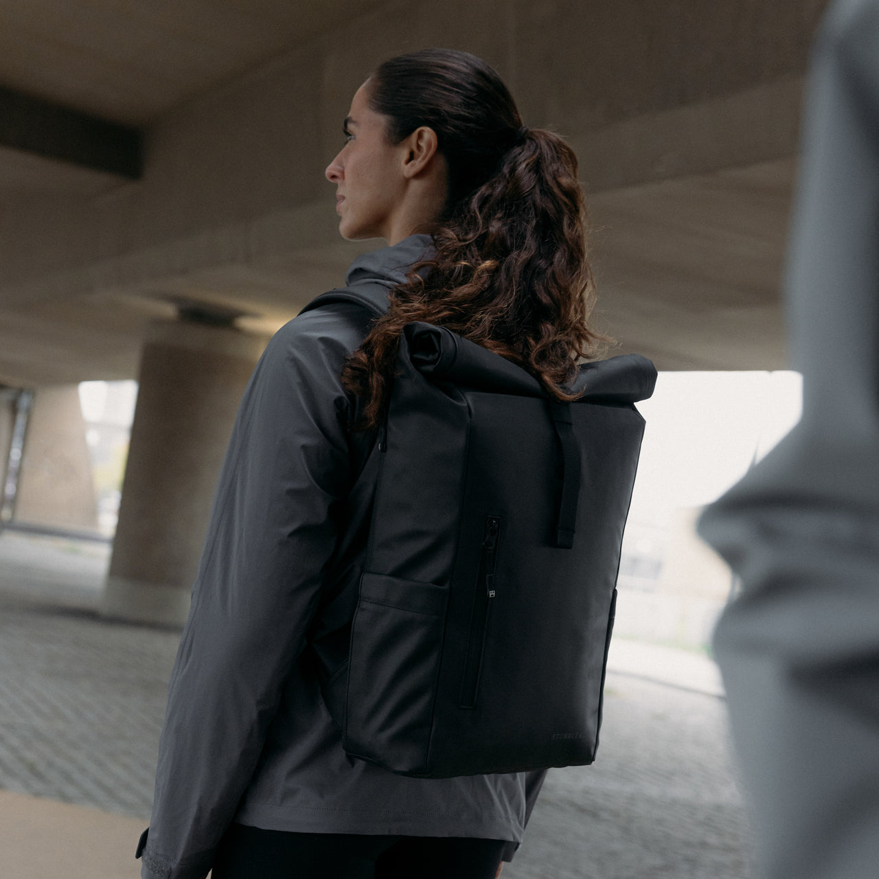 A woman wearing an All Black Roll Top 20L