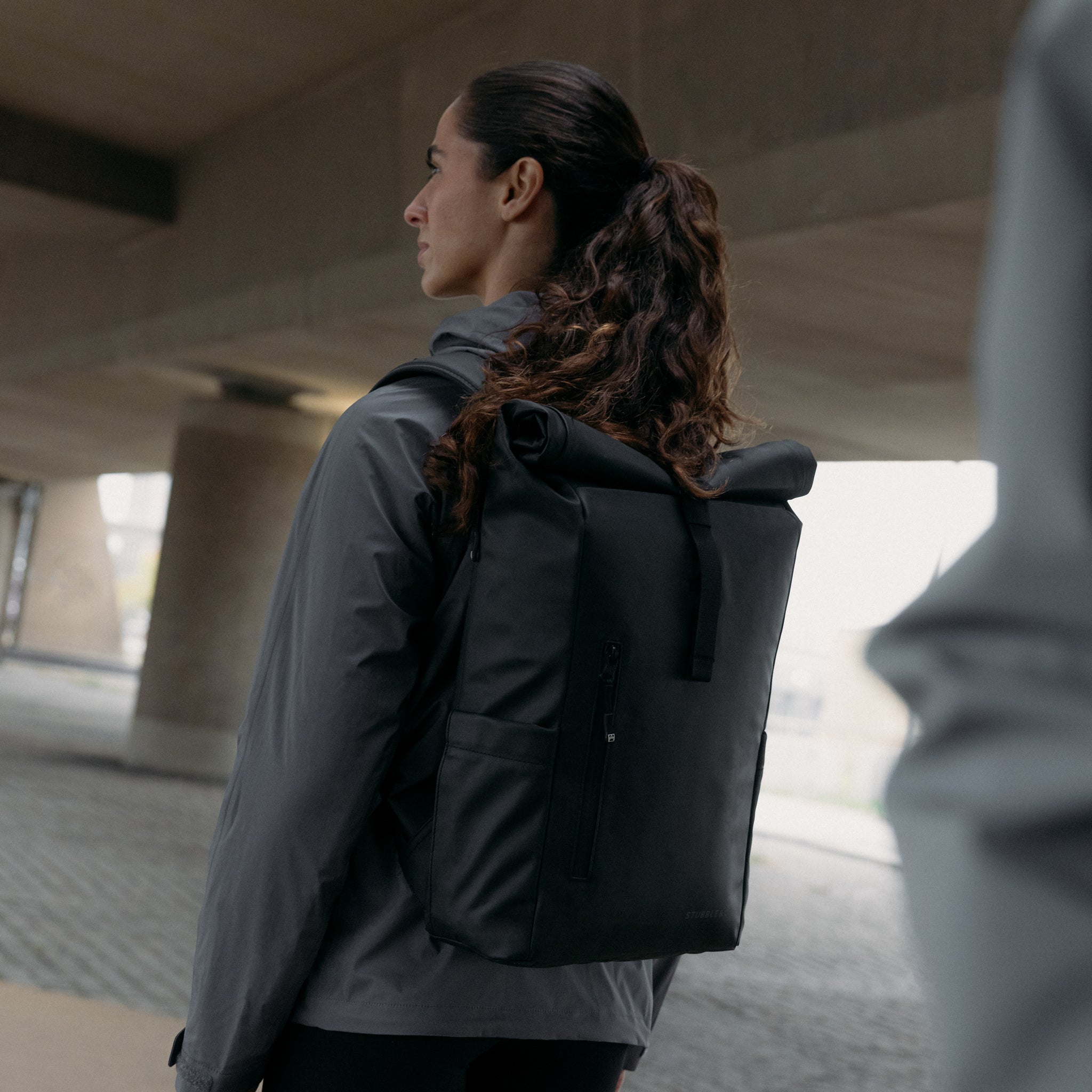 A woman wearing an All Black Roll Top 20L