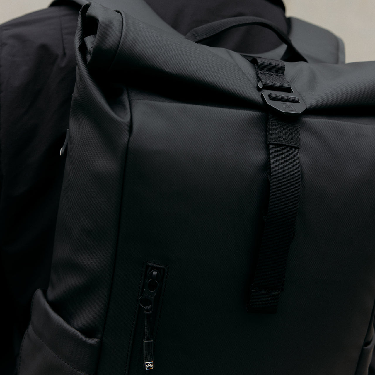 A close up of the g-hook on a Roll Top 15l backpack in All Black
