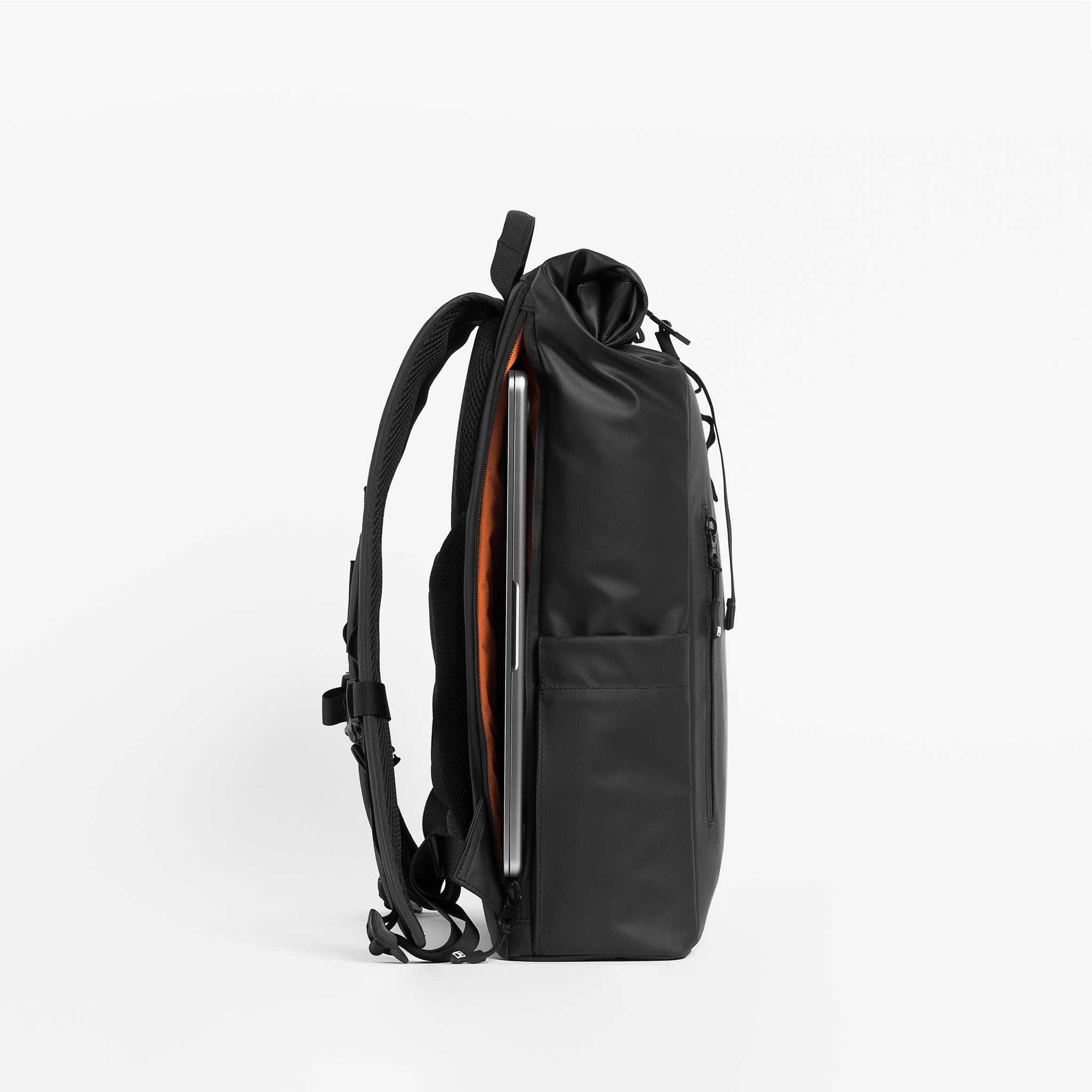 Side product shot of The Roll Top 15L in All Black with a latop in the unzipped laptop compartment.