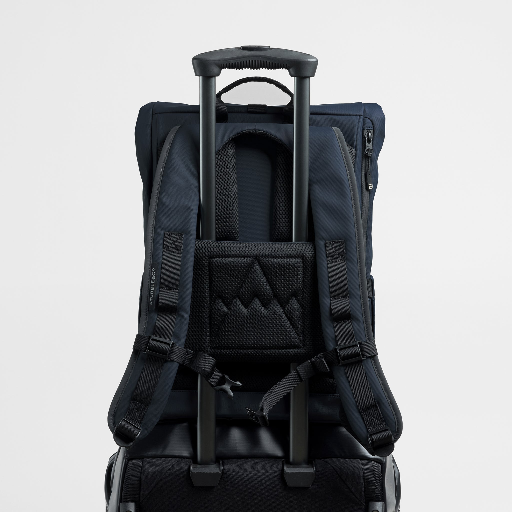 A studio shot of a Midnight Blue Roll Top 15L on a suitcase using the luggage sleeve