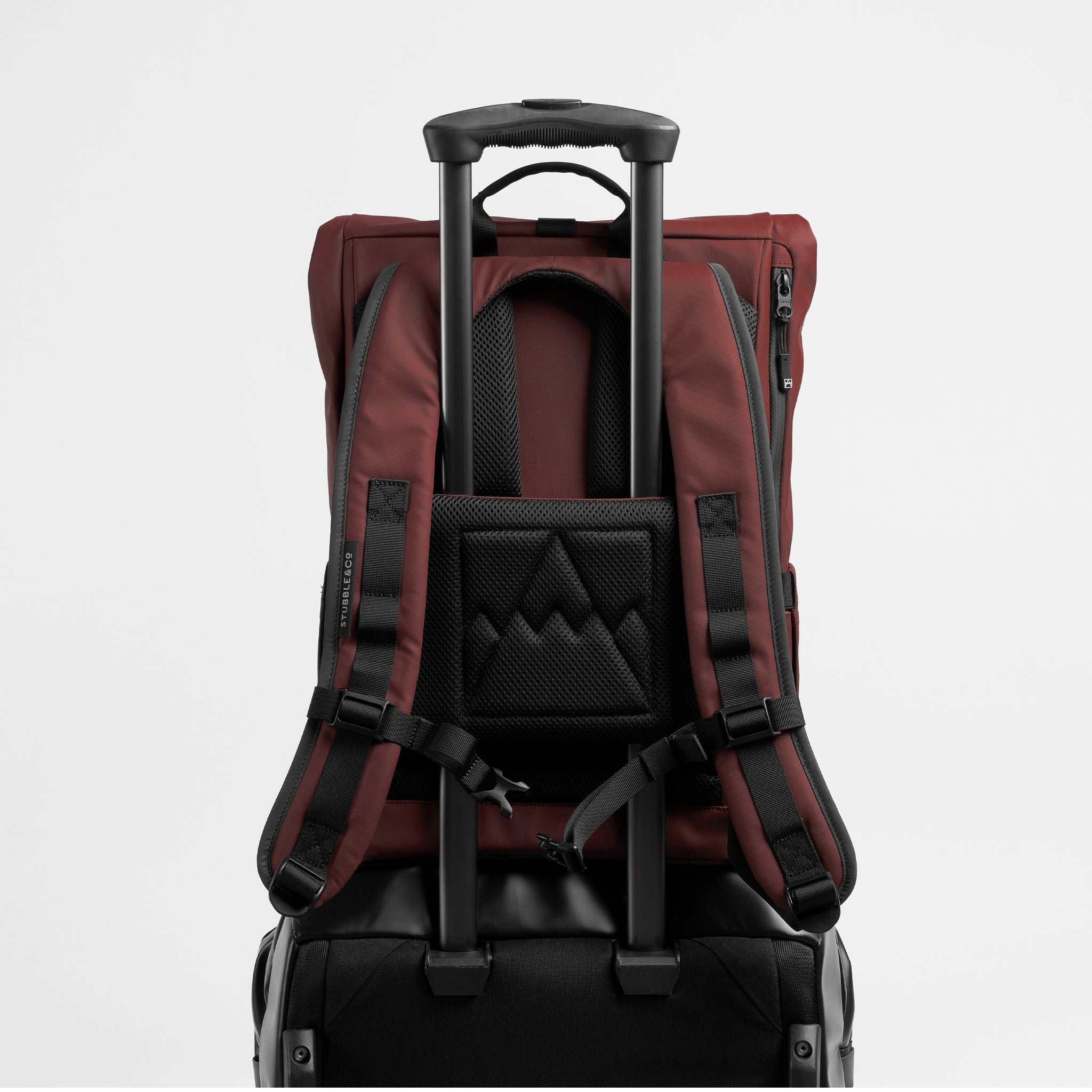 A studio shot of the Garnet Red Roll Top 15L on a suitcase using the luggage sleeve