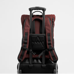 A studio shot of the Garnet Red Roll Top 15L on a suitcase using the luggage sleeve