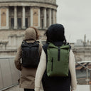 Two people wearing the Roll Top 15L in Urban Green in a city
