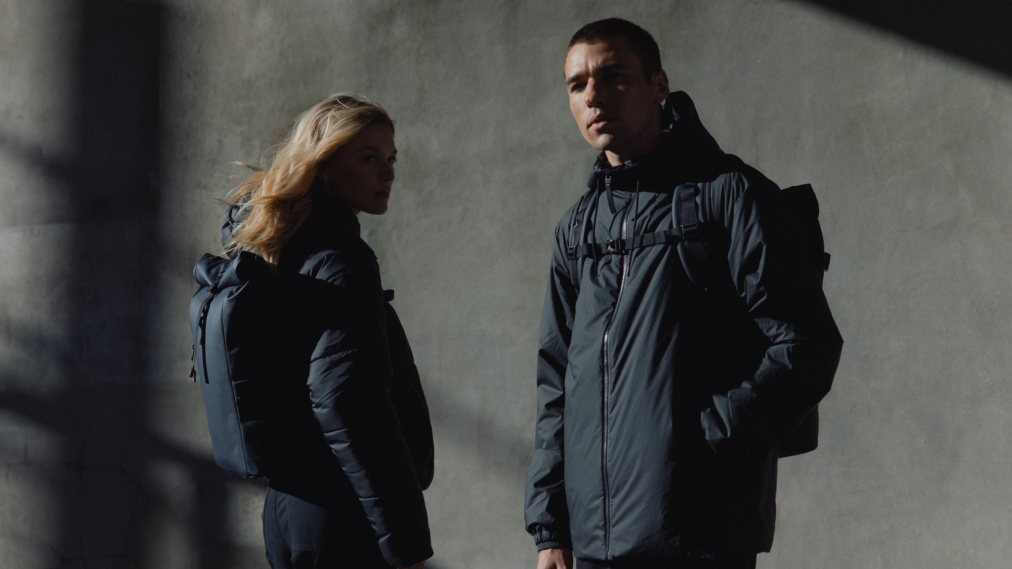 A man and woman wearing roll top 20l and roll top 15l on their backs in Midnight Blue