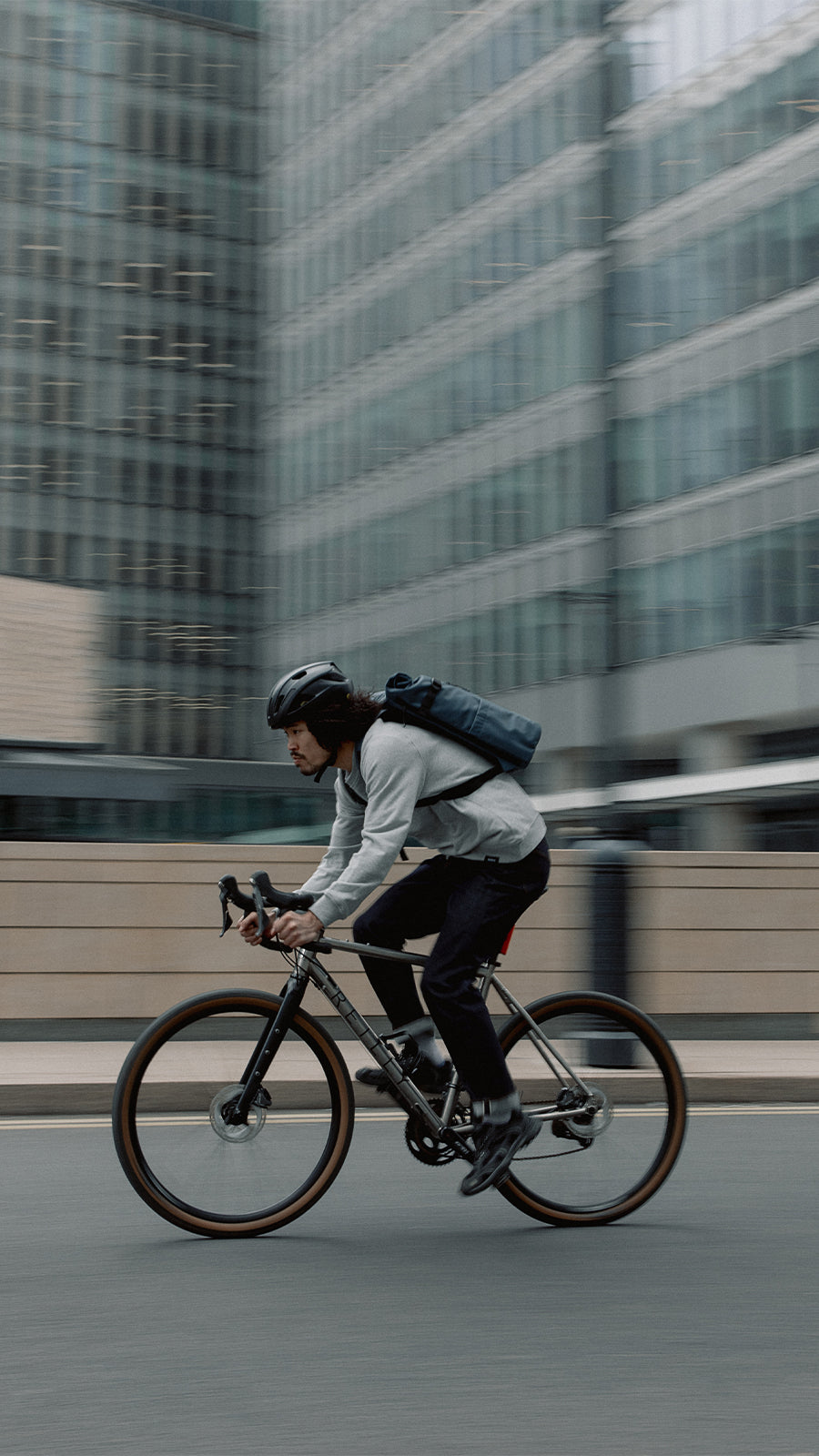 A man cycling through London with a Roll Top 20l in Tasmin Blue on his back