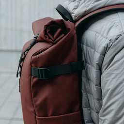 A close up of the roll on the Roll Top 20L in Garnet Red on a mans bag