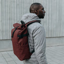 A man wearing a Roll Top 20L in Garnet Red on his back