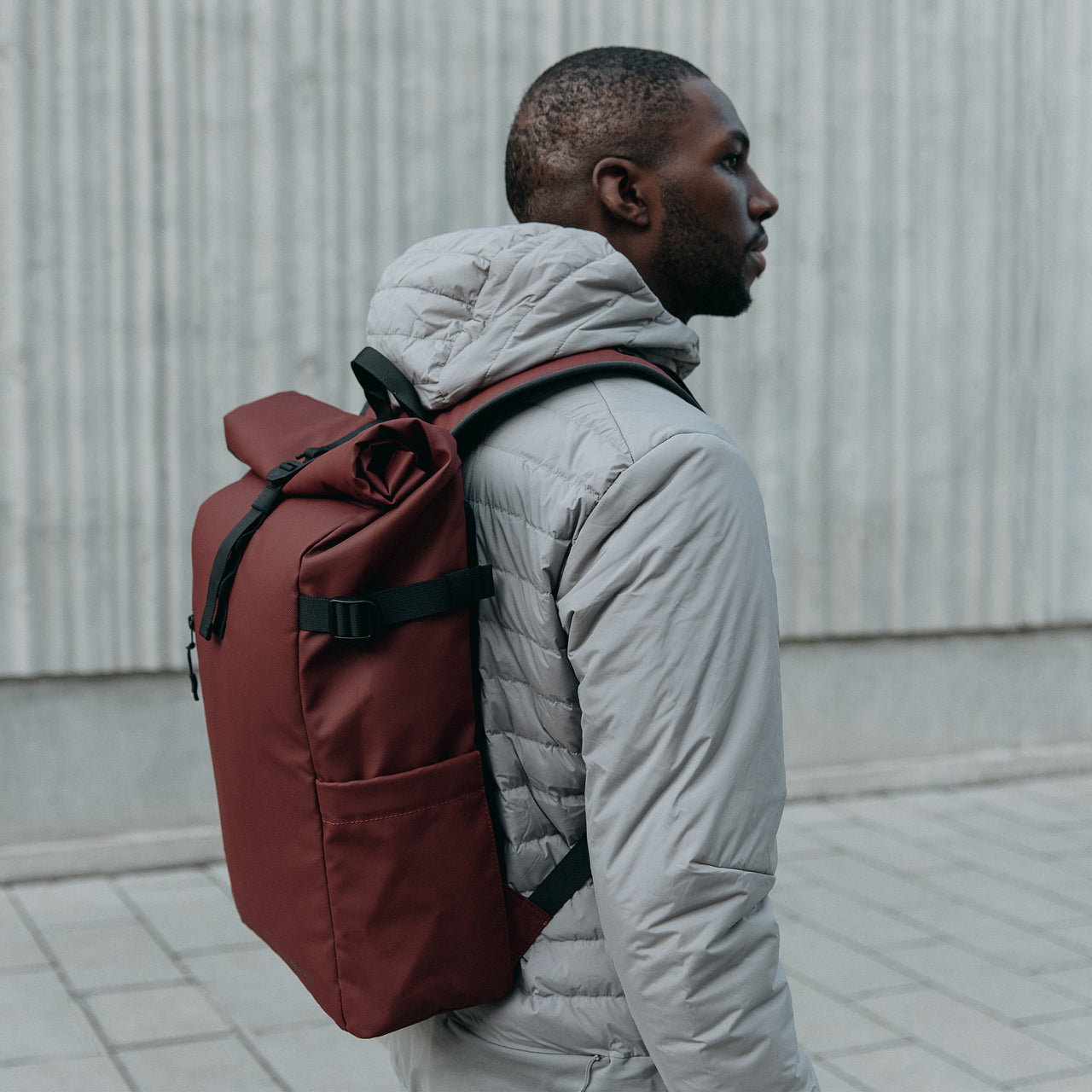 A man wearing a Roll Top 20L in Garnet Red on his back