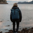 Women wearing The Roll Top 20L backpack in Tasmin Blue by water